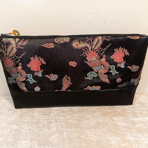 May include: Black satin zippered pouch with a colorful embroidered design of phoenixes and flowers.