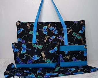 May include: A black tote bag, a medium zippered pouch, and a small rectangular pouch, all featuring a vibrant dragonfly pattern in shades of blue, green, and gold. The bags have bright blue straps and trim, with a drawstring bag at the base.