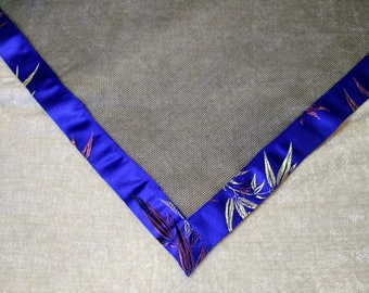 May include: A close-up of a corner of a black mesh fabric with a blue satin trim. The trim has a floral pattern in gold and purple.