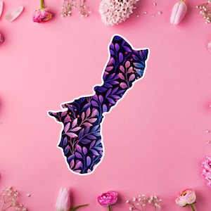 May include: A sticker in the shape of Guam, featuring a floral design in shades of purple, pink, and blue against a black background. The sticker is surrounded by pink flowers and a pink background.
