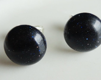 May include: A pair of silver stud earrings with round, black, glittery stones.