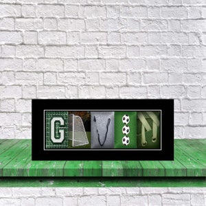 Op de afbeelding: Een ingelijste zwart-witfoto van de naam "GAVIN" gespeld met behulp van afbeeldingen die verband houden met voetbal. De letter "G" is een voetbaldoel, de letter "A" is een voetbal, de letter "V" is een voetbalschoen en de letter "N" is een voetbal.