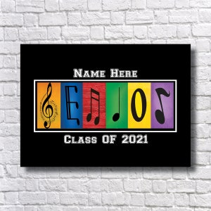 May include: Black and white graduation sign with the word "SENIORS" spelled out using musical notes in colorful boxes. The text "NAME HERE" and "CLASS OF 2021" are also included.