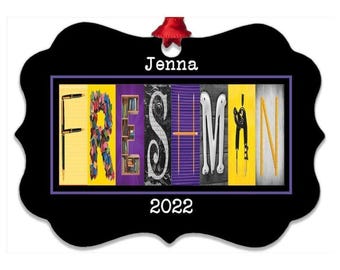 May include: A black, scalloped-edge ornament featuring the name Jenna and the year 2022. The center displays the word FRESHMAN spelled out with letters formed by various school-themed objects like pens, books, and a compass on a yellow background.