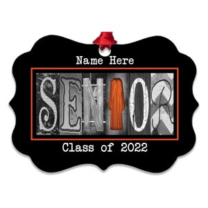 May include: Black and white ornament with the word "Senior" in a collage style with a red graduation gown in the middle. The ornament has a red ribbon and the text "Name Here" and "Class of 2022" in white.