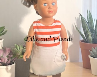 May include: A doll with brown curly hair wearing a white and orange striped sleeveless shirt and a white skirt with a pocket and a button. The doll is wearing white shoes. The doll is standing on a wooden surface. The text "Lillie and Friends" is visible on the doll's shirt.