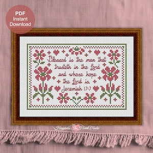 May include: A cross-stitch pattern in a brown frame featuring the text Blessed is the man that trusteth in the Lord and whose hope the Lord is. Jeremiah 17:7. The design includes pink flowers and green leaves with a decorative border on white fabric.