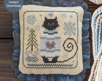 May include: A square cross-stitch pattern featuring a black cat wearing a light blue sweater with a small cat face graphic. The design includes a green pine tree, blue snowflakes, and a swirling tail, all bordered by a dark blue ruffled fabric trim.