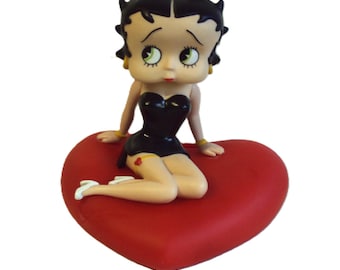 Plastic piggy bank from the 1970s depicting Betty Boop sitting on a heart-shaped cushion.