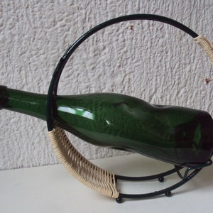 Metal and wicker bottle holder with its bottle and dating from the 1970s.