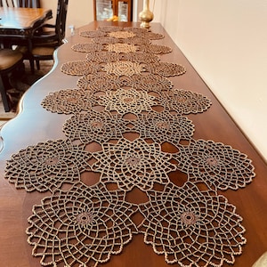 May include: A gold beaded table runner with a delicate, intricate design. The runner is made of small, round beads that are woven together to create a beautiful pattern. The runner is perfect for adding a touch of elegance to any table setting.