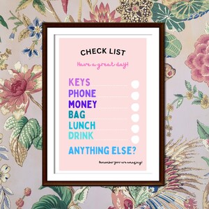 Könnte beinhalten: Eine rosa Checkliste mit dem Text "CHECK LIST" in Schwarz. Die Checkliste enthält folgende Punkte: Schlüssel, Telefon, Geld, Tasche, Mittagessen, Getränk und sonst noch etwas? Der Text "Have a great day!" ist in Schwarz und der Text "Remember you are amazing!" ist in Lila.