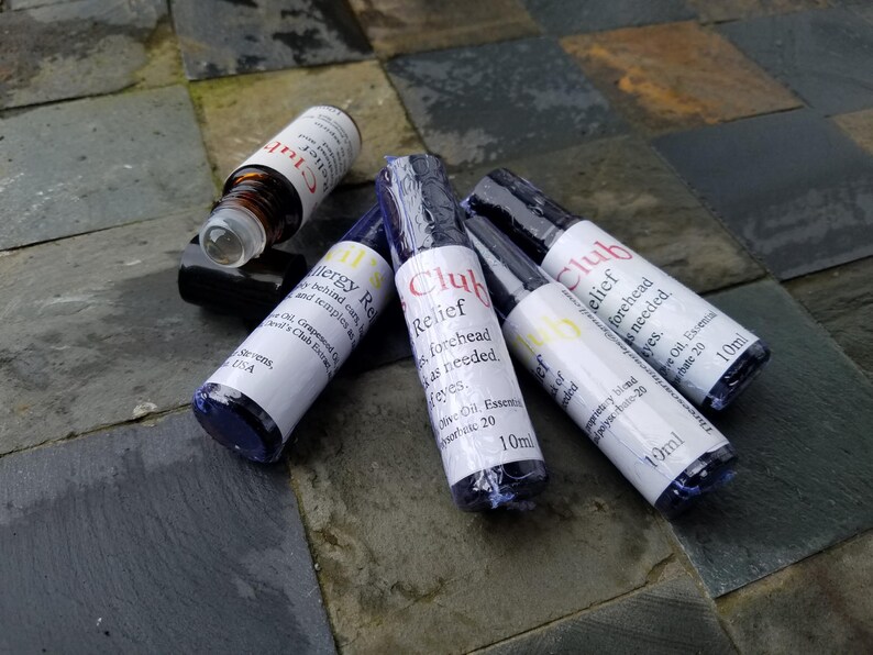K&ouml;nnte beinhalten: Mehrere kleine, zylindrische Flaschen mit wei&szlig;en Etiketten und schwarzen Kappen liegen auf einer Steinoberfl&auml;che. Die Etiketten tragen die Aufschrift "Club Relief" und "Allergy Relief". Die Flaschen enthalten &auml;therische &Ouml;le, Volumen 10 ml.