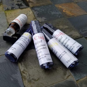 K&ouml;nnte beinhalten: Mehrere kleine, dunkelblaue Glasflaschen mit wei&szlig;en Etiketten und schwarzen Verschl&uuml;ssen. Die Etiketten tragen die Aufschrift "Club Relief" und "Allergy Relief" in roter und schwarzer Schrift. Jede Flasche enth&auml;lt 10 ml.