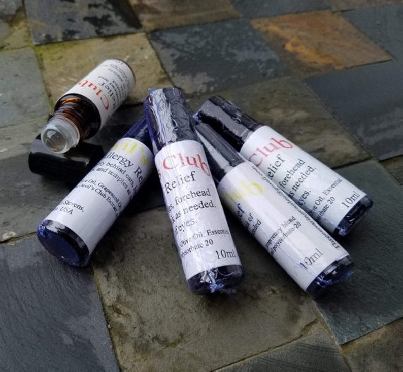 K&ouml;nnte beinhalten: Mehrere kleine, dunkelblaue Glasflaschen mit wei&szlig;en Etiketten und schwarzen Verschl&uuml;ssen. Die Etiketten tragen die Aufschrift "Club Relief" und "Allergy Relief" in roter und schwarzer Schrift. Jede Flasche enth&auml;lt 10 ml.