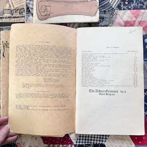 Puede incluir: Un libro abierto con p&aacute;ginas envejecidas y amarillentas. La p&aacute;gina izquierda contiene texto, mientras que la p&aacute;gina derecha muestra una tabla de contenidos. El libro se titula "The Arduin Grimoire Vol II" y est&aacute; fechado. El libro est&aacute; sobre un edred&oacute;n de retazos.