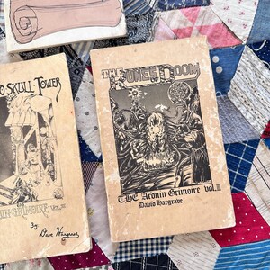 Puede incluir: Libros de fantas&iacute;a vintage con ilustraciones en blanco y negro. Un libro se titula "The Dunes of Doom" y otro "Skull Tower". Los libros est&aacute;n sobre un edred&oacute;n de retazos colorido.