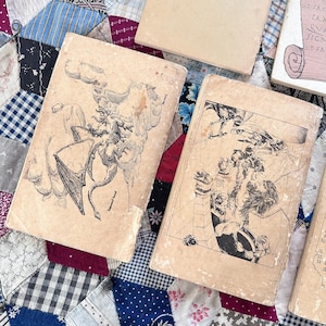Puede incluir: Varios libros antiguos con cubiertas desgastadas est&aacute;n colocados sobre un edred&oacute;n de retazos. Las cubiertas de los libros presentan ilustraciones detalladas en blanco y negro de criaturas y escenas fant&aacute;sticas. Los libros son de varios tama&ntilde;os y condiciones, lo que sugiere que son antiguos o usados.