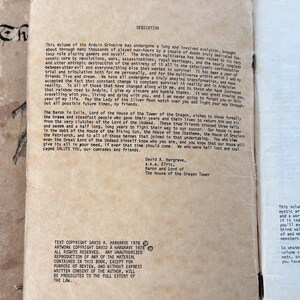 Puede incluir: P&aacute;gina de un libro antiguo con texto de dedicatoria e informaci&oacute;n de derechos de autor. El texto est&aacute; impreso en tinta negra sobre papel crema envejecido. La p&aacute;gina es de un libro de juegos de rol de fantas&iacute;a.
