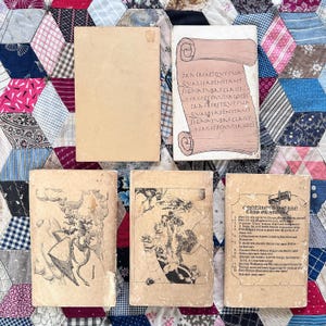 Puede incluir: Una colecci&oacute;n de libros antiguos con cubiertas desgastadas. Un libro presenta un dise&ntilde;o de pergamino con texto, mientras que otros muestran ilustraciones y texto. Los libros est&aacute;n dispuestos sobre un edred&oacute;n de retazos.