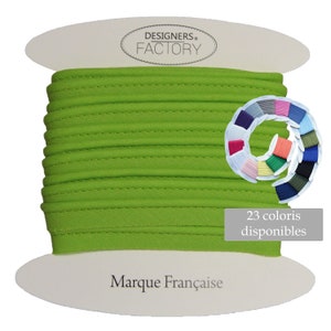 May include: A spool of bright green fabric trim with a stitched edge. The trim is labelled "DESIGNERS FACTORY" and "Marque Française". A colour chart shows 23 different colours available.