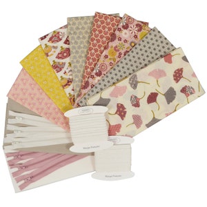 Könnte beinhalten: Ein Stoffpaket mit verschiedenen floralen und geometrischen Mustern in Rosa-, Gelb- und Grautönen. Das Paket enthält zwei Spulen weißen Gummibands, zwei Reißverschlüsse und zwei rosa Reißverschlüsse. Die Gummibandspulen sind mit "Marque Française" beschriftet.