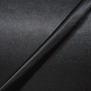 May include: A close-up of a black fabric with a subtle shimmer. The fabric is folded in half, creating a diagonal line across the image.