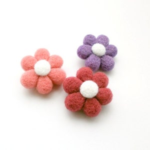 May include: Three felt flower embellishments in pink, red, and purple. Each flower has a white centre.