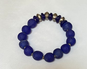 May include: A blue glass bead bracelet with silver metal spacers. The bracelet is made of round beads with a matte finish.