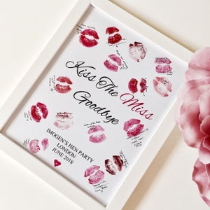 May include: White framed sign with the text "Kiss The Miss Goodbye" and a heart at the bottom. The sign is decorated with red lipstick kisses and handwritten messages.