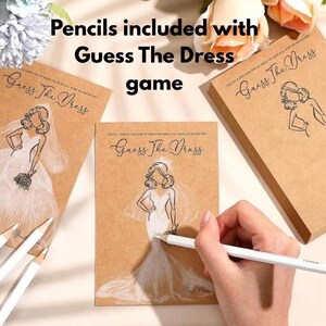 Puede incluir: Un juego de despedida de soltera con el texto "Guess The Dress" en tarjetas de papel kraft. El juego incluye l&aacute;pices para dibujar el vestido de novia. La imagen muestra una mano dibujando un vestido en una de las tarjetas.