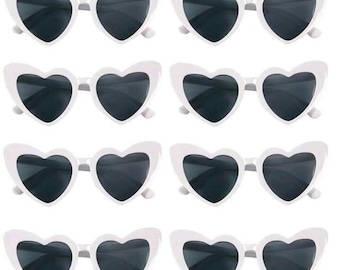May include: Eight pairs of white heart-shaped sunglasses with black lenses.