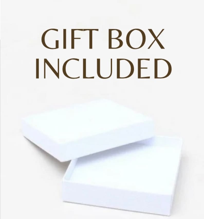 Może przedstawiać: Białe pudełko prezentowe z otwartą pokrywką. Tekst "GIFT BOX INCLUDED" jest nadrukowany brązowymi literami na białym tle.