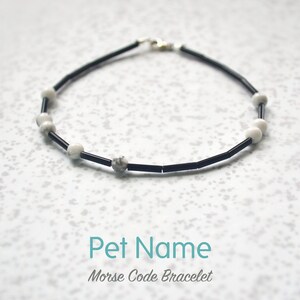 May include: Black and white beaded bracelet with a silver clasp. The bracelet has the text "Pet Name Morse Code Bracelet" below it.