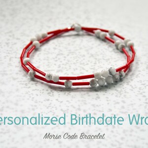 May include: A red and white beaded bracelet with a silver clasp. The bracelet is a Morse code bracelet and says "Personalized Birthdate Wrap".