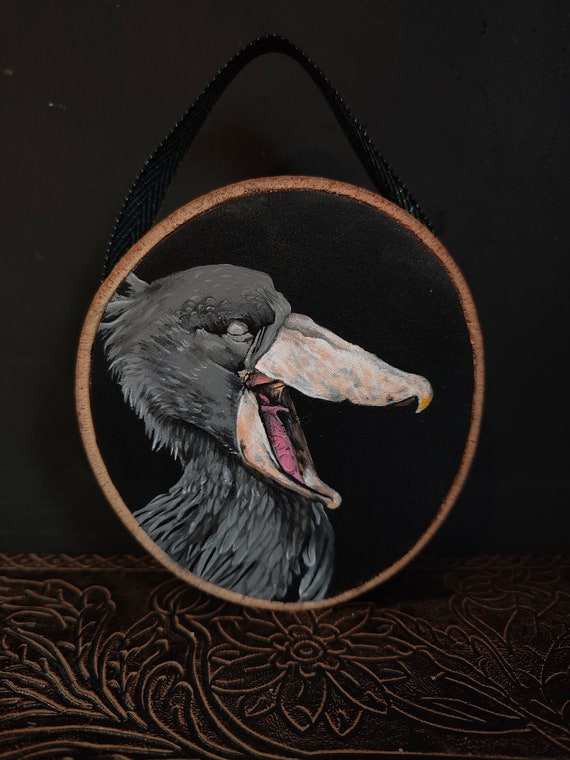 A shoebill — one of nature's most hilariously menacing birds — immortalized in acrylics on an actual wood slice; weird wildlife art at its best.