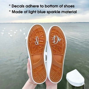 May include: A pair of white canvas shoes with brown soles. The soles have the words "I Do" and "I" written on them in light blue.