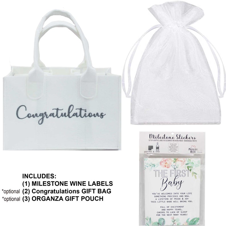 May include: A white gift bag with the word "Congratulations" printed on it, a white organza gift pouch, and a set of milestone stickers for a baby's first year. The stickers feature a floral design and the text "The First Baby".