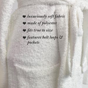 May include: A white, fluffy robe made of polyester. The robe features belt loops and pockets. Text on the image reads: "luxuriously soft fabric", "made of polyester", "fits true to size", and "features belt loops & pockets."