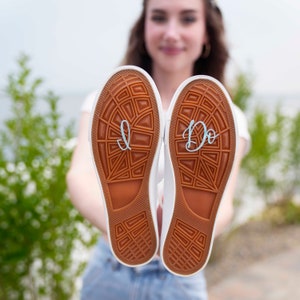May include: A pair of white canvas shoes with the words "I Do" and "I" written on the soles.