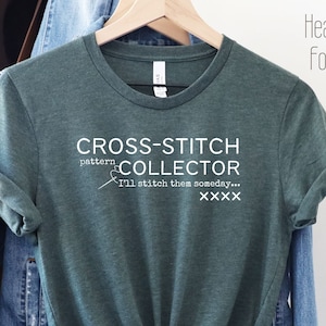 May include: A green t-shirt with the text "CROSS-STITCH pattern COLLECTOR I'll stitch them someday... XXXX" in white. Heather Forest.