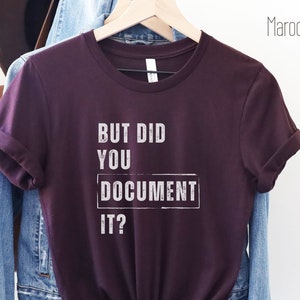Peut inclure: Un t-shirt marron avec le texte "But did you document it?" en blanc. Le texte est dans une police de caractères vieillie.