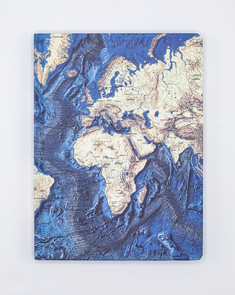 Puede incluir: Un cuaderno azul y beige con un mapa del mundo en relieve. El mapa muestra los continentes y oc&eacute;anos del mundo.