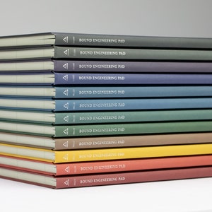 May include: A pile of bound engineering pads with covers in various colours, including green, blue, yellow, and red. Each pad has the text "BOUND ENGINEERING PAD" printed on the cover in white.
