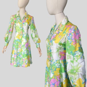 May include: A vintage floral print dress with a long sleeve, a collared neckline, and a button-up front. The dress is in shades of green, yellow, pink, and blue.