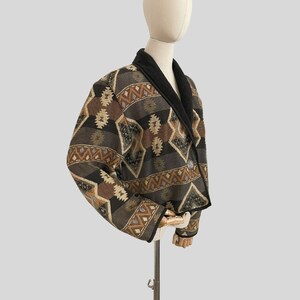 May include: A patterned blazer with a black collar and a single button closure. The jacket features a geometric design in shades of brown, gray, and tan. The blazer is displayed on a mannequin.