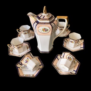May include: A vintage porcelain tea set with a pink and white floral design. The set includes a teapot, sugar bowl, creamer, and six cups and saucers.