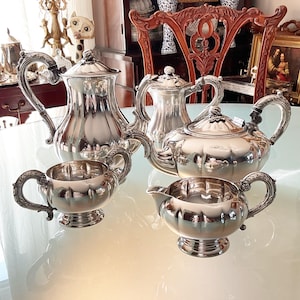 May include: A silver tea set comprising a teapot, creamer, sugar bowl, and a coffee pot. The set features a classic design with a fluted pattern and decorative handles.
