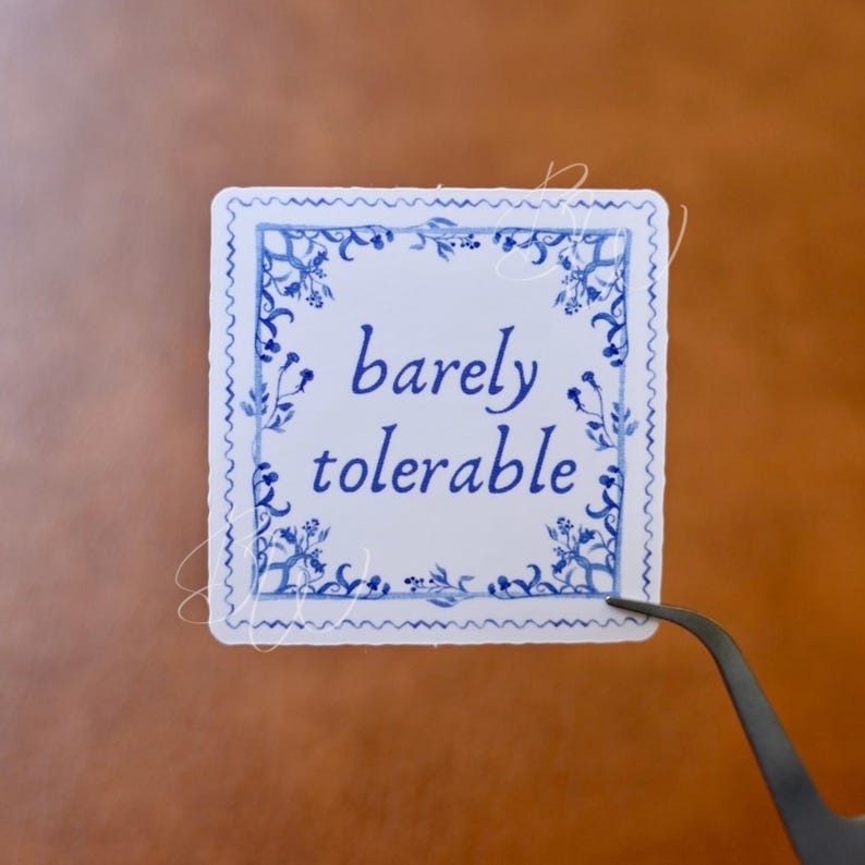 May include: A white square sticker with a blue and white floral border. The text "barely tolerable" is written in blue cursive lettering.