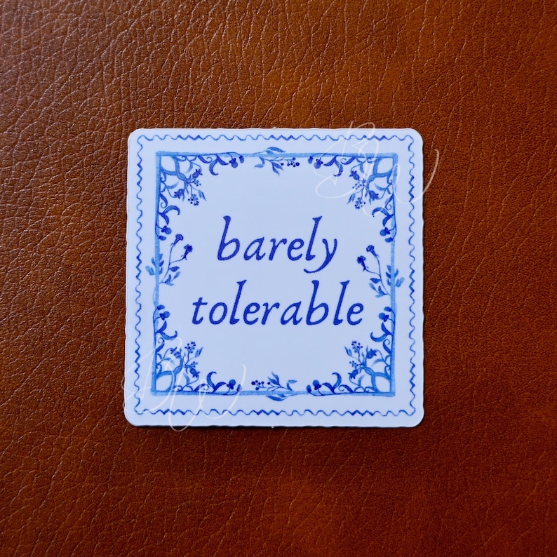 May include: White sticker with a blue and white floral border. The text "barely tolerable" is written in blue cursive font.